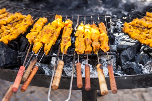 Marinated grilled pork on skewers over embers