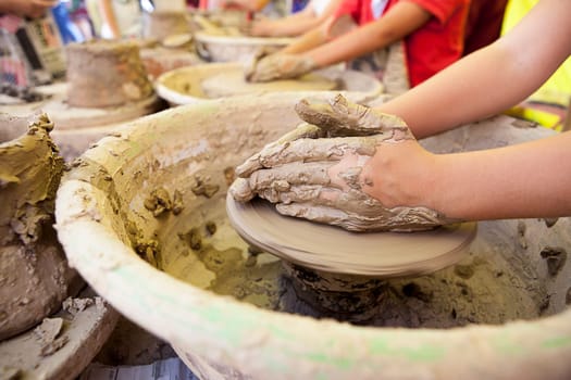 Children learning to work with potter's wheel