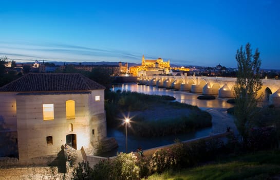 Saint Antonio Watermill on the Guadalquivir in Cordoba, Spain. Night scene with some couples sitting and the Mosque at bottom