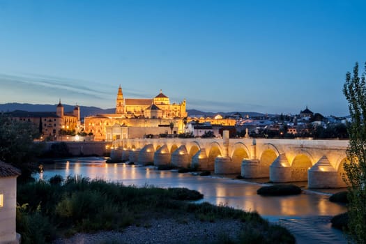 Saint Antonio Watermill on the Guadalquivir in Cordoba, Spain. Night scene with some couples sitting and the Mosque at bottom