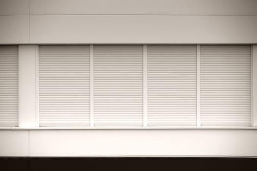 A series of modern windows of a commercial building with enclosed blinds.