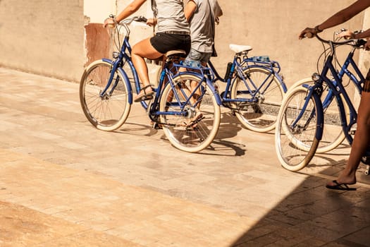Four young women walking in the city with bicycles. Malaga old town