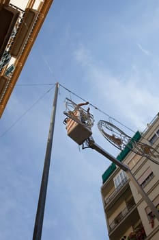 Electrician stays on cherry picker and repairs electric city decoration