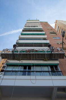 Workers over elevator for painting high buildings walls