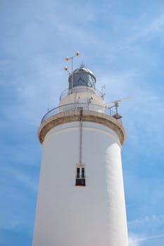A white whitewashed lighthouse isolated over blue sky with clouds