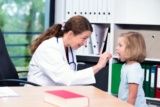 female pediatrician in white lab coat examined little girl