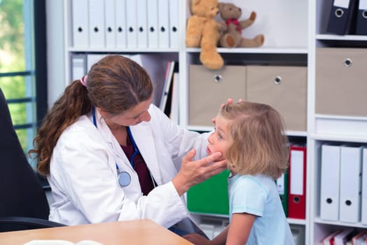 female pediatrician in white lab coat examined little girl