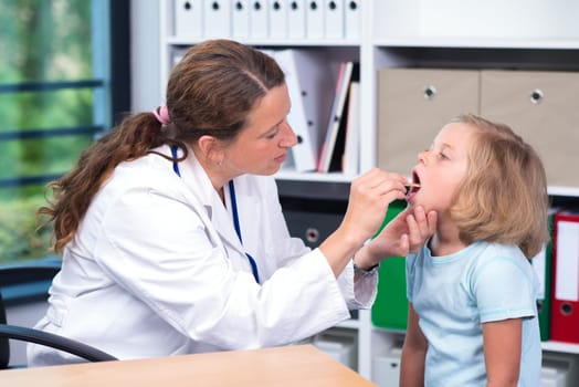 female pediatrician in white lab coat examined little girl