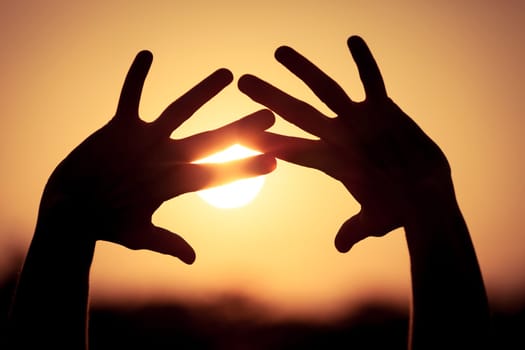 silhouette of female hands during sunset
