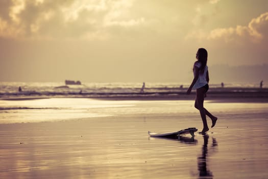 silhouette of a surfer sitting near the ocean during sunset