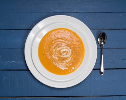 plate of pumpkin soup on a blue wooden table