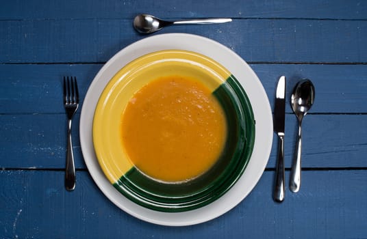 plate of pumpkin soup on a blue wooden table