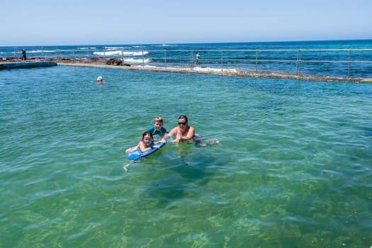 Family mother son daughter swimming in beach sea concrete tidal pool