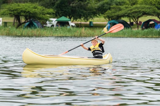 Young boy on holiday canoeing on dam waters