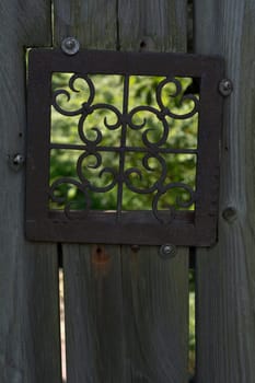 Old Fence with Metal Design Window Looking into the Garden