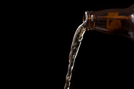 Beer Pouring From Bottle with black background.