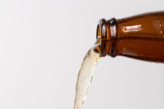 Beer Puring From Bottle with grey/white background with bubbles in the beer.