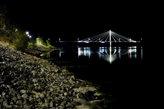 Cable Bridge in Umeå, Sweden at night with reflections in the water.