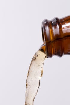 Beer Pouring out of Bottle with bubbles in the beer on white background.