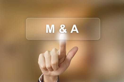 business hand pushing merger and acquisition button on blurred background