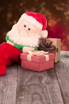 Santa Claus toy leaning against the gift boxes close-up