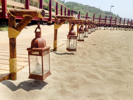 Oriental hanging brass lanterns beside the wooden walk of the beach