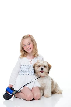 Portrait of a little girl sitting down with her dog. She is looking at the camera and smiling.