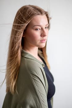 Side View portrait of a beautiful young woman taken in a studio on a grey background.