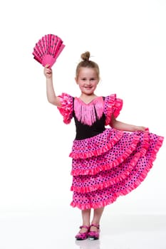 Young girl dressed as a flamenco dancer with a white background. The girl is looking at the camera and smiling.