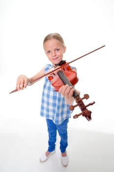 Little girl playing a violin on a white background. She is looking at the camera and smiling.