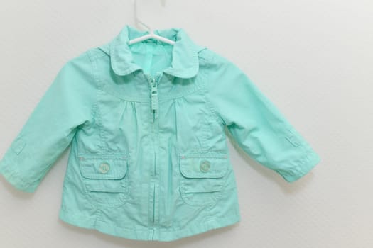 Menthol colored jacket for girl hanging on hanger on white background