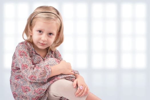 Cute little girl sitting in front of windows