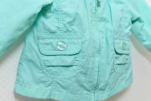 Menthol colored jacket for girl hanging on hanger on white background