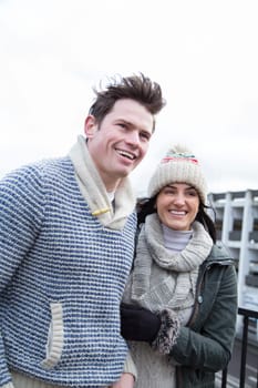 Attractive young couple walking in the city. They are both wrapped up in the cold and laughing at something together.