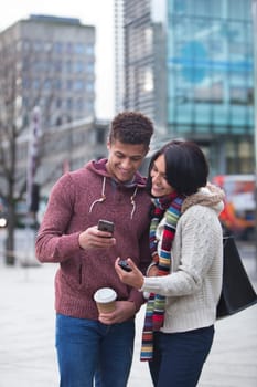 Young couple standing together in the city, looking at a smart phone