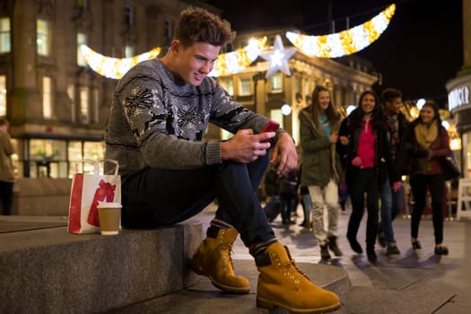 Young man looking at a smart phone in the city at evening
