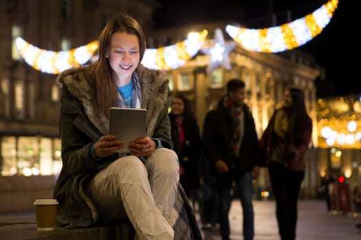Young woman looking at a digital tablet in the city at evening