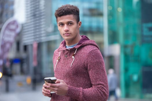 Young, mixed-race man in the city with a smart phone
