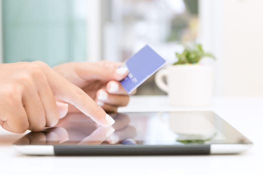 closeup hand using tablet and credit card shopping online