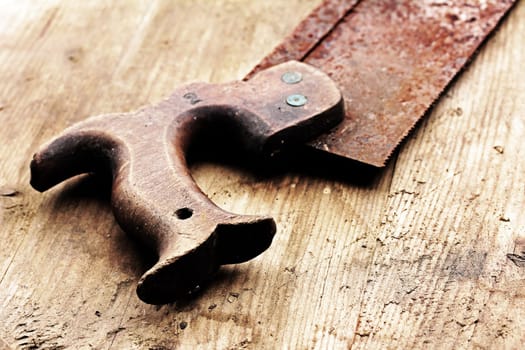An old rusty saw on a wooden table