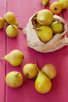 Fresh ripe pears in paper bag on wooden background