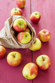 Fresh ripe apples in paper bag on wooden background