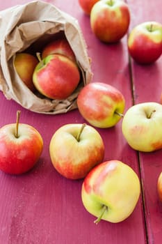 Fresh ripe apples in paper bag on wooden background