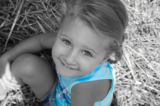 little girl sits in the hay on the farm