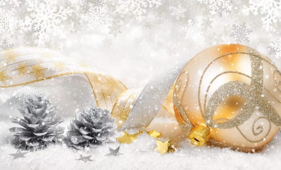 Elegant Christmas arrangement with a beautiful gold bauble,nice ribbons,silver cones,lots of snow and ornamental large snowflakes in the background