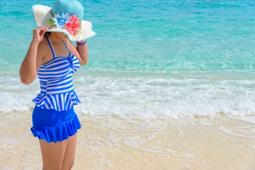 Tourist girl in a blue white striped swimsuit standing with happiness on the beautiful beach and sea during summer at Koh Miang Island, Mu Ko Similan National Park, Phang Nga province, Thailand