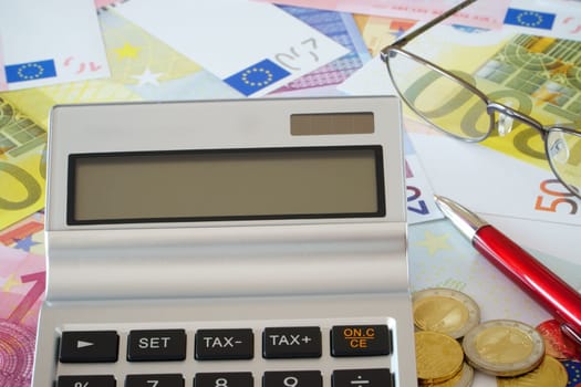 Calculator,glasses and ballpoint pens on Euro notes