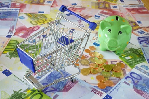 Shopping trolley on Euro money certificates with piggy bank