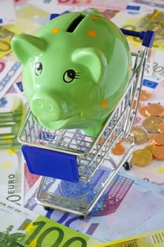 Green savings note in a shopping cart on euro banknotes