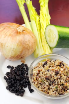 A small bowl of cooked three colors of quinoa.cooked with some of the raw ingredients shown next to it on a plate..